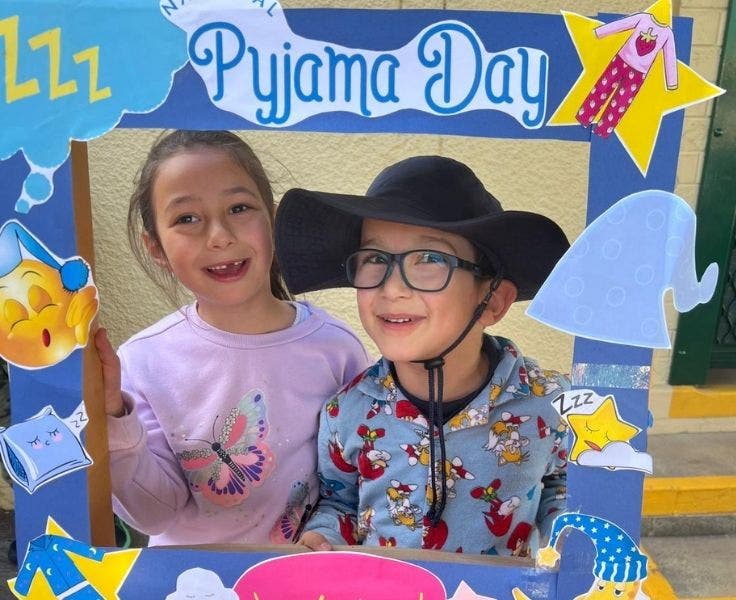 A girl and boy wearing pyjamas and posing in a Pyjama Day frame.