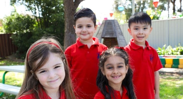 Four kindergarten students smiling.