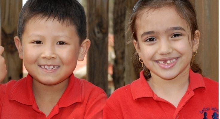 Two kindergarten students smiling to camera.