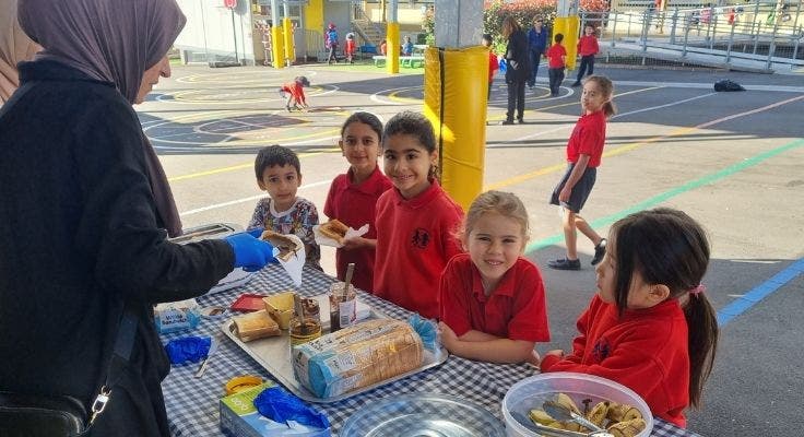Students and parent at breakfast club table of food.