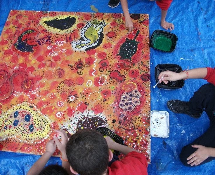 Aerial shot of students painting an artwork using tradition Aboriginal art techniques as part of NAIDOC Week.
