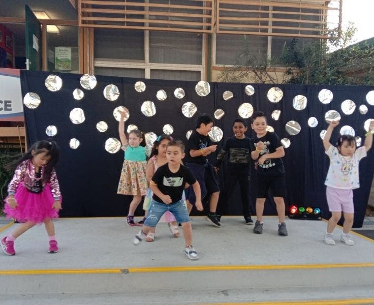 Students in mufti clothes, dancing on a stage during a school disco.