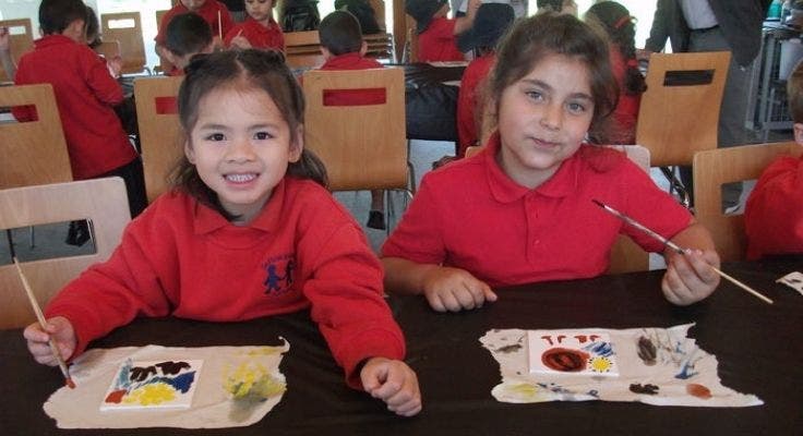 Two female students sitting and painting.