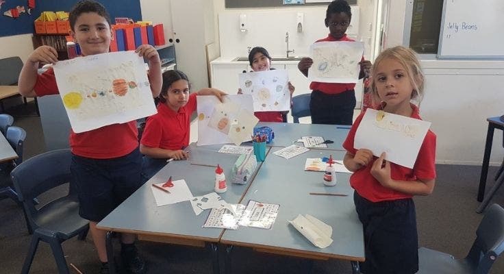 Four Year 1 and 2 students displaying their representations of the solar system.