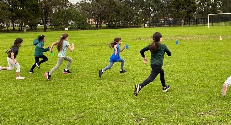 Back view of five students running at an athletics carnival.