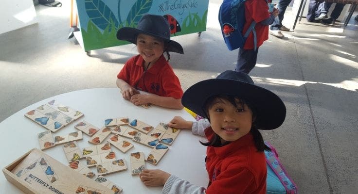 Two kindergarten girls completing a puzzle on a low table.