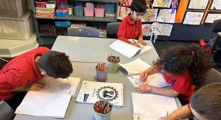 Four students writing at their desks.