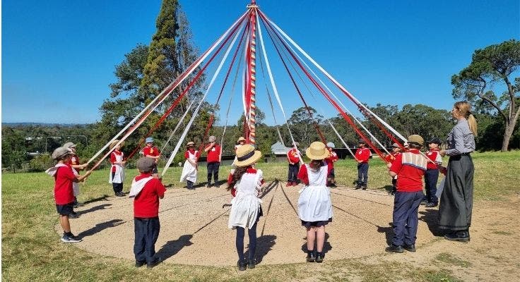 Students dancing around a maypole as part of a history excursion.